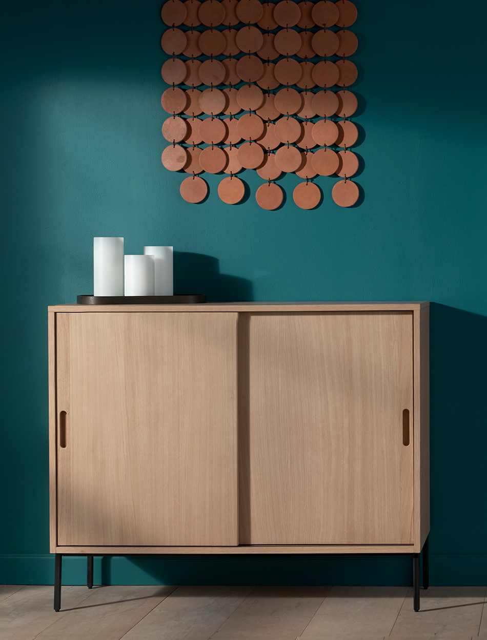 Wood storage cabinet in naturally lit room with ocean colored walls